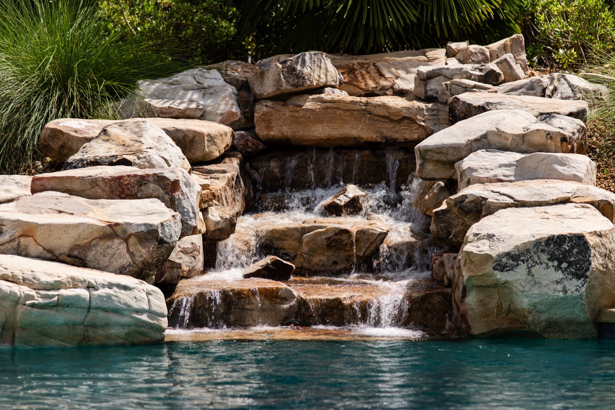 Natural rock waterfall entering a swimming pool