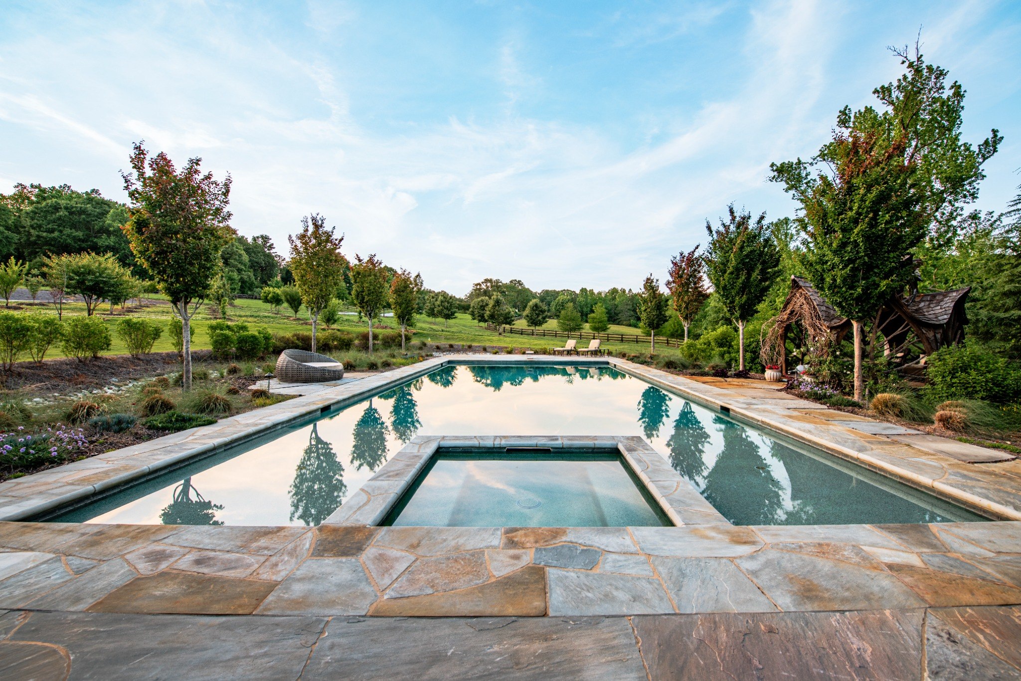 Expansive swimming pool and spa surrounded by landscaping