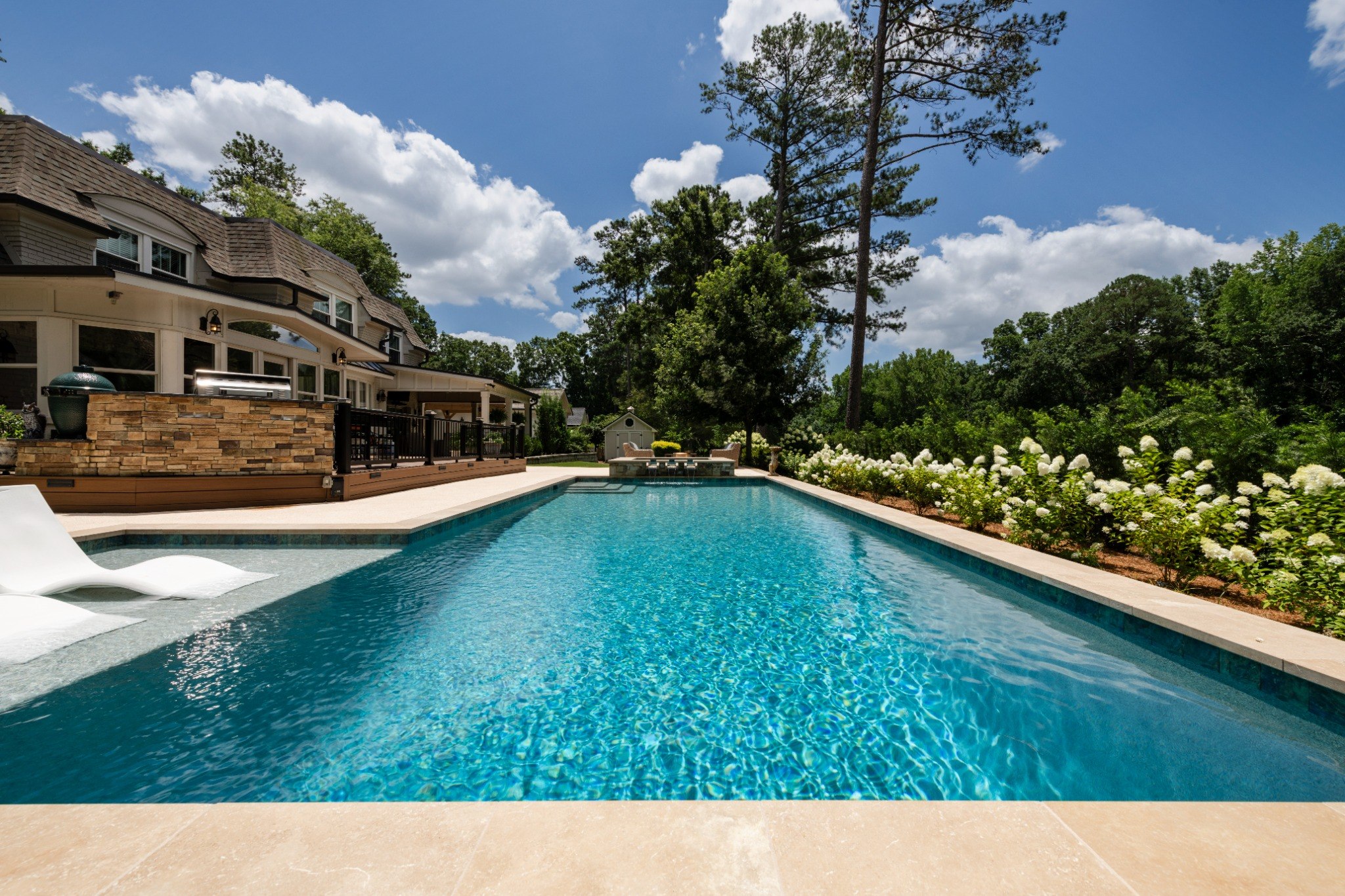 Long blue pool framed by hydrangeas and trees