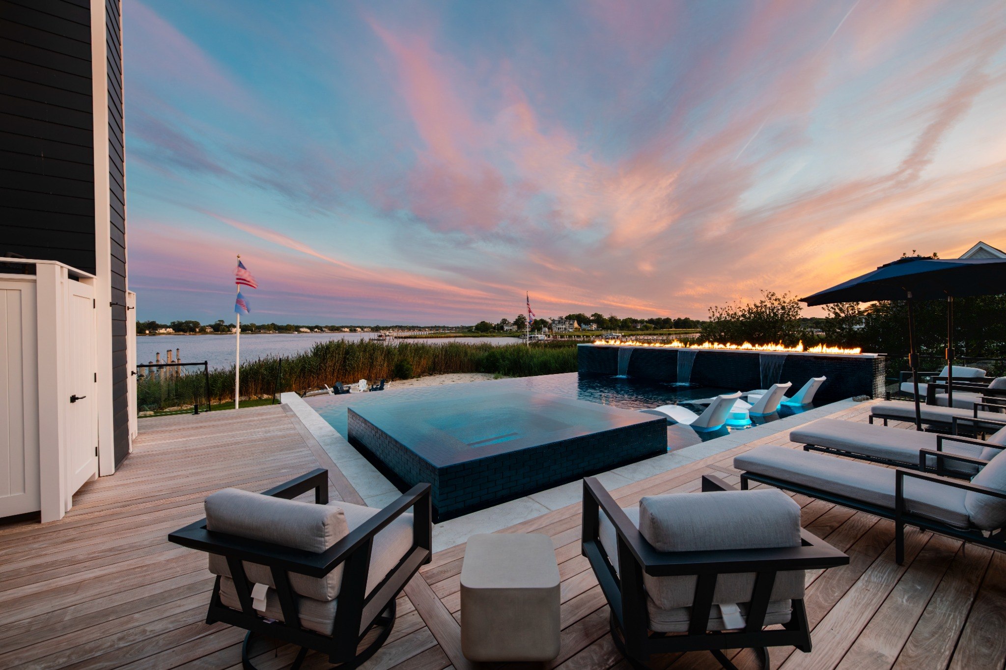 Waterfront pool with fire feature at sunset